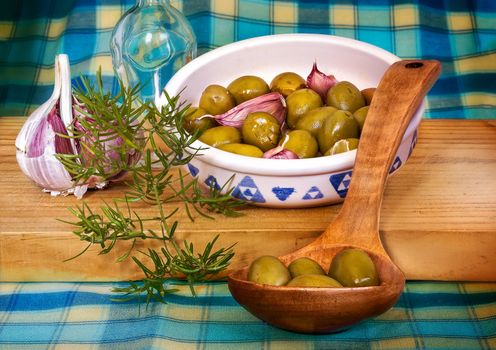 Green olives on a wooden spoon over wood table,