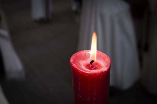 Red Candle burning with an orange flame in darkness