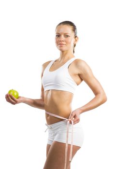 young athletic girl measuring waist measuring tape and holding a green apple, concept of healthy eating, isolated on white background