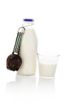Drinking milk. Milk bottle and glass of milk with traditional cow bell isolated on white background. Traditional milk drinking, dairy concept.