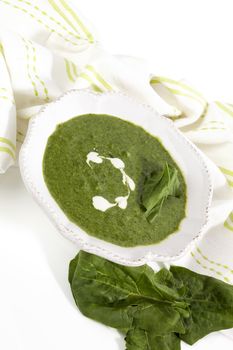 Delicious spinach soup with fresh spinach leaves isolated on white background. Healthy soup eating.