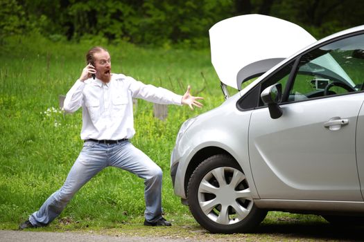 Driver furious with mobile phone a broken car by the road 