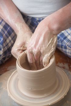 Hands of a potter, creating an earthen jar on the circle