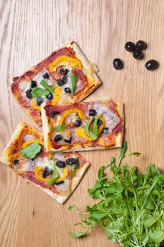 Puff pastry cake with ruccola and olives on the wooden table