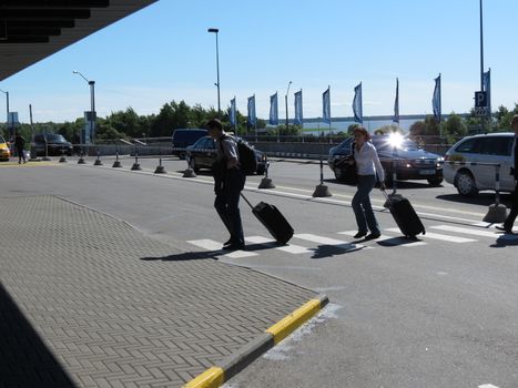 TALLINN, CIRCA JUNE 2012 - Travellers carrying their trolley at the zebra crossing in front of the airport in Tallinn, june 2012