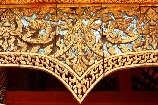 the detail of ancient thai decorated pattern that include handcraft wood carving work,gold painting and decorated with gold plate,mirror and precious stone,Lampang temple,Thailand