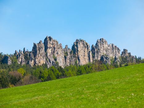 Sharp sand stone rock formation with green meadow and blue sky