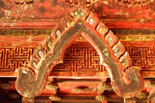 the detail of ancient thai decorated pattern that include handcraft wood carving work,gold painting and decorated with gold plate,mirror and precious stone,Lampang temple,Thailand