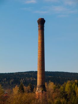 Tall industrial factory chimney located in the nature