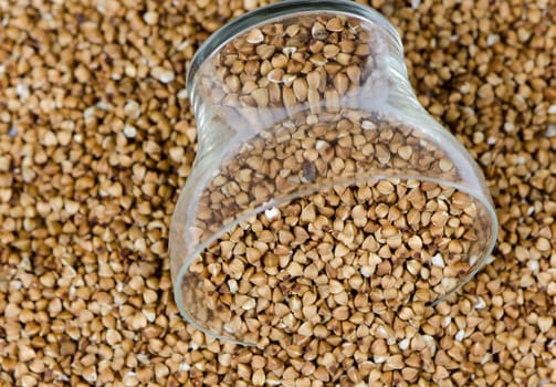 small cup of raw eco food buckwheat pile background