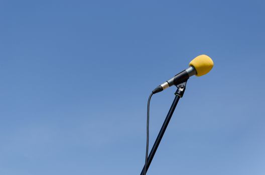 yellow microphone with stand on blue sky background