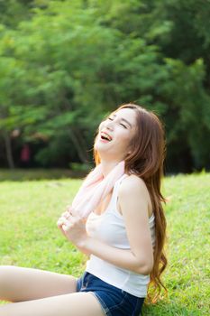 Woman sitting tired after jogging. Located on the lawn in the park.