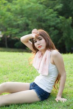 Woman sitting tired after jogging. Located on the lawn in the park.