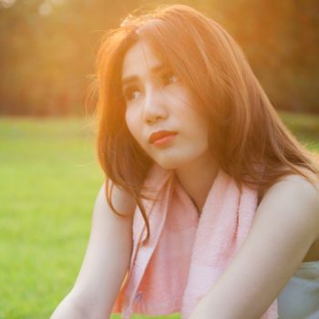 Woman sitting on lawn in park., In the evening, with the sun warm.