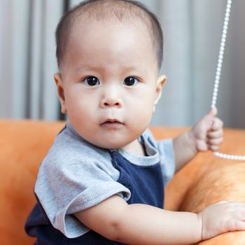 Baby boy.child Asian., And played on the orange sofa.