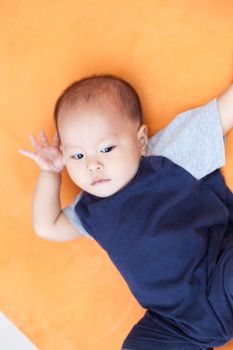 Baby boy.child Asian., And is lying on the orange sofa