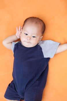 Baby boy.child Asian., And is lying on the orange sofa
