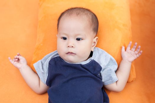 Baby boy.child Asian., And is lying on the orange sofa