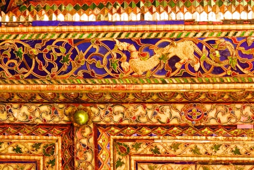 the detail of ancient thai decorated pattern that include handcraft wood carving work,gold painting and decorated with gold plate,mirror and precious stone,Lampang temple,Thailand