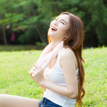 Woman sitting tired after jogging. Located on the lawn in the park.