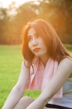 Woman sitting on lawn in park., In the evening, with the sun warm.
