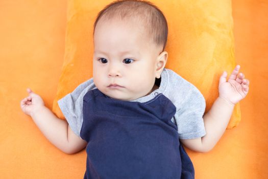 Baby boy.child Asian., And is lying on the orange sofa