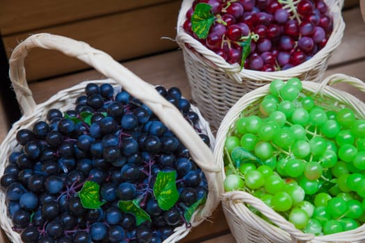 Red, green and black grape in wood basket.