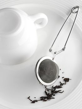 dry tea, strainer, cup on white plate