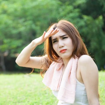 Woman sitting tired after jogging. Located on the lawn in the park.