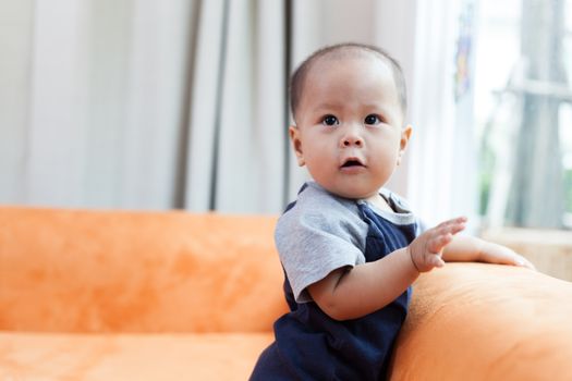 Baby boy.child Asian., And played on the orange sofa.