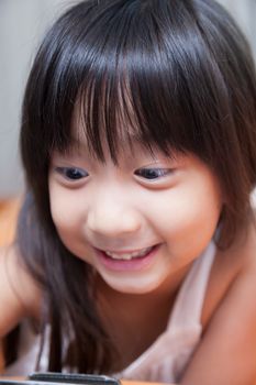 Girl playing with tablet. Lying on the orange sofa at home.girl smiling.