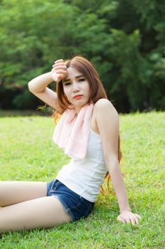 Woman sitting tired after jogging. Located on the lawn in the park.