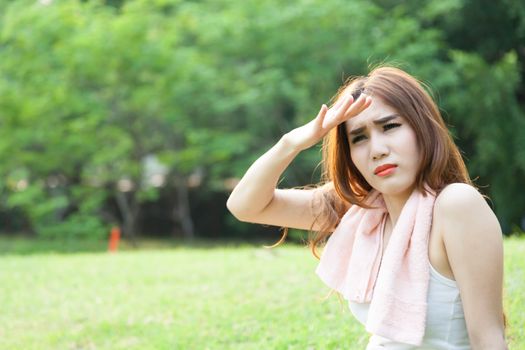 Woman sitting tired after jogging. Located on the lawn in the park.
