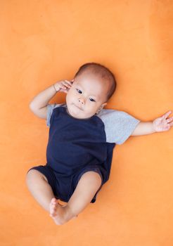 Baby boy.child Asian., And is lying on the orange sofa