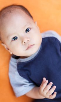 Baby boy.child Asian., And is lying on the orange sofa