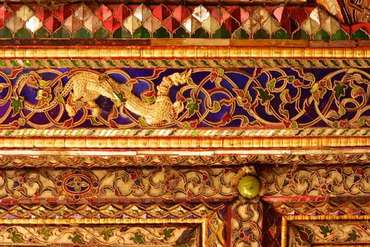 the detail of ancient thai decorated pattern that include handcraft wood carving work,gold painting and decorated with gold plate,mirror and precious stone,Lampang temple,Thailand