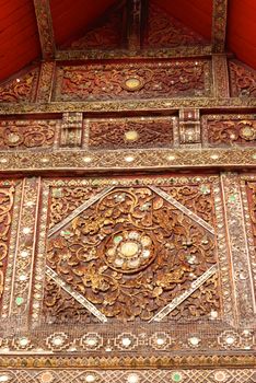 the detail of ancient thai decorated pattern that include handcraft wood carving work,gold painting and decorated with gold plate,mirror and precious stone,Lampang temple,Thailand