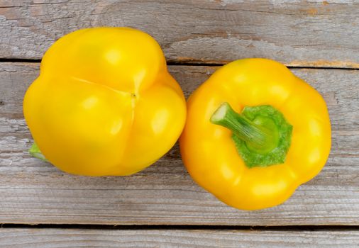 Two Ripe Yellow Bell Peppers isolated on Rustic Wooden background. Top View