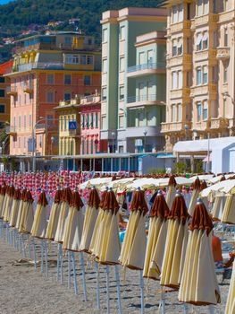 Umbrellas in a row over the beach, buildings on the back