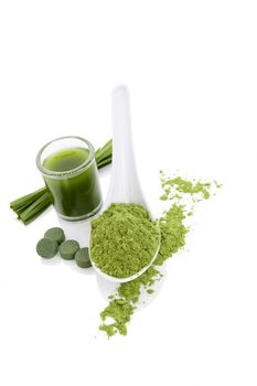 Green algae dietary supplements. Wheatgrass ground, chlorella and spirulina pills, blades of grass and green drink isolated over white background. Green spring detox.