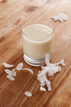 Coconut milk on wooden background with coconut flakes. Vegan milk drinking concept.