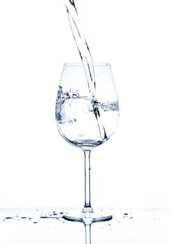 Glass with the stream of dinking water on white background