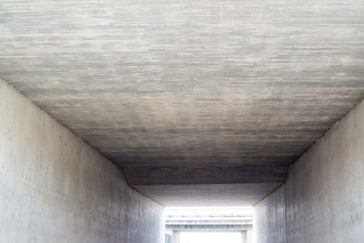 Abstract: Inside a concrete tunnel with light coming in from the exit or entrance.