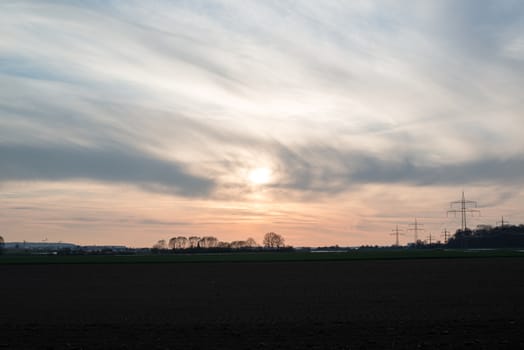 Dramatic and beautiful spring sunset view with trees, fields and a city in the background