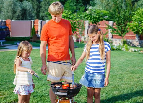 Happy family on vacation having barbecue outdoors