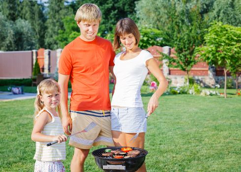 Happy family on vacation having barbecue outdoors