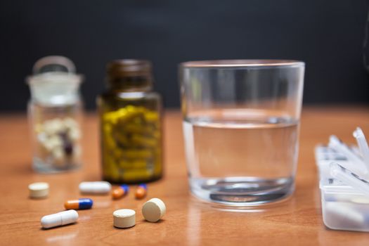 Old bottle of pills along with a few pills above a wooden table