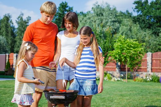 Happy family on vacation having barbecue outdoors