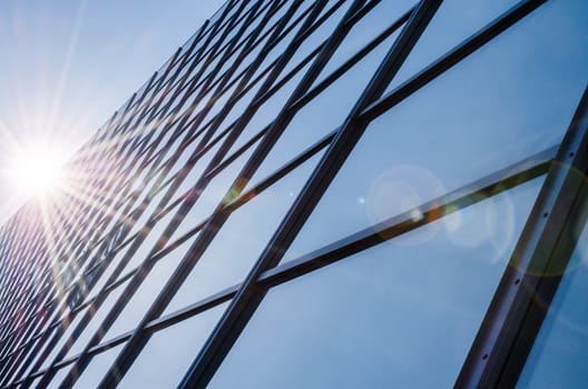 Glass and steel - mirrored facade of modern office building with sunbeams glare reflection