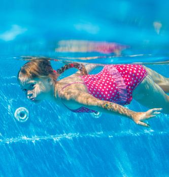 The cute girl swimming underwater and smiling